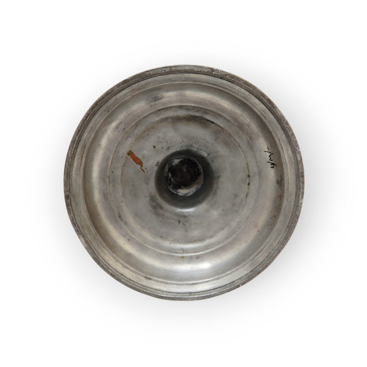 Underside of the pewter candlestick's base, showing concentric lathe-turning rings and a central turning boss