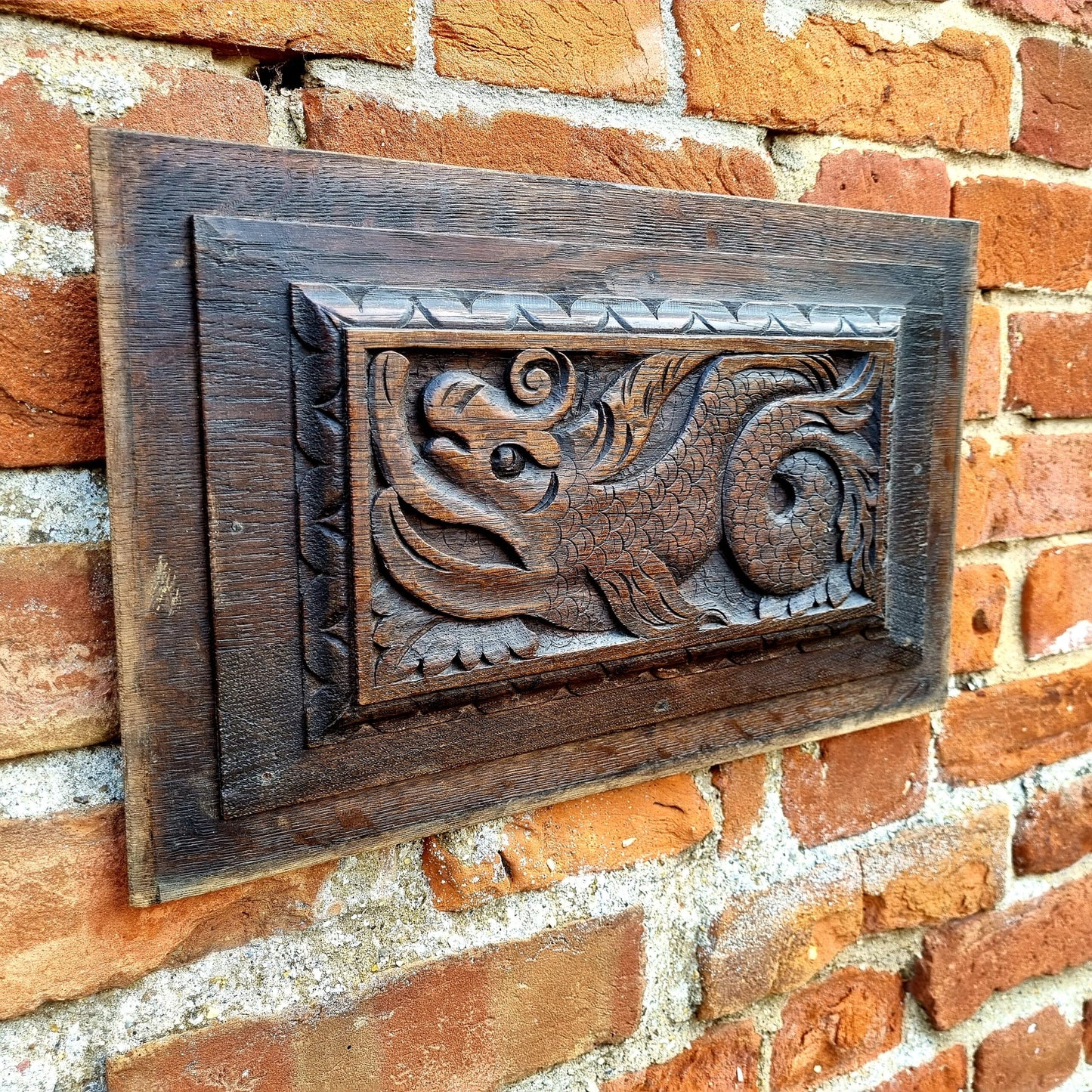A pair of early 17thC antique carved oak panels depicting stylised mythical sea creatures