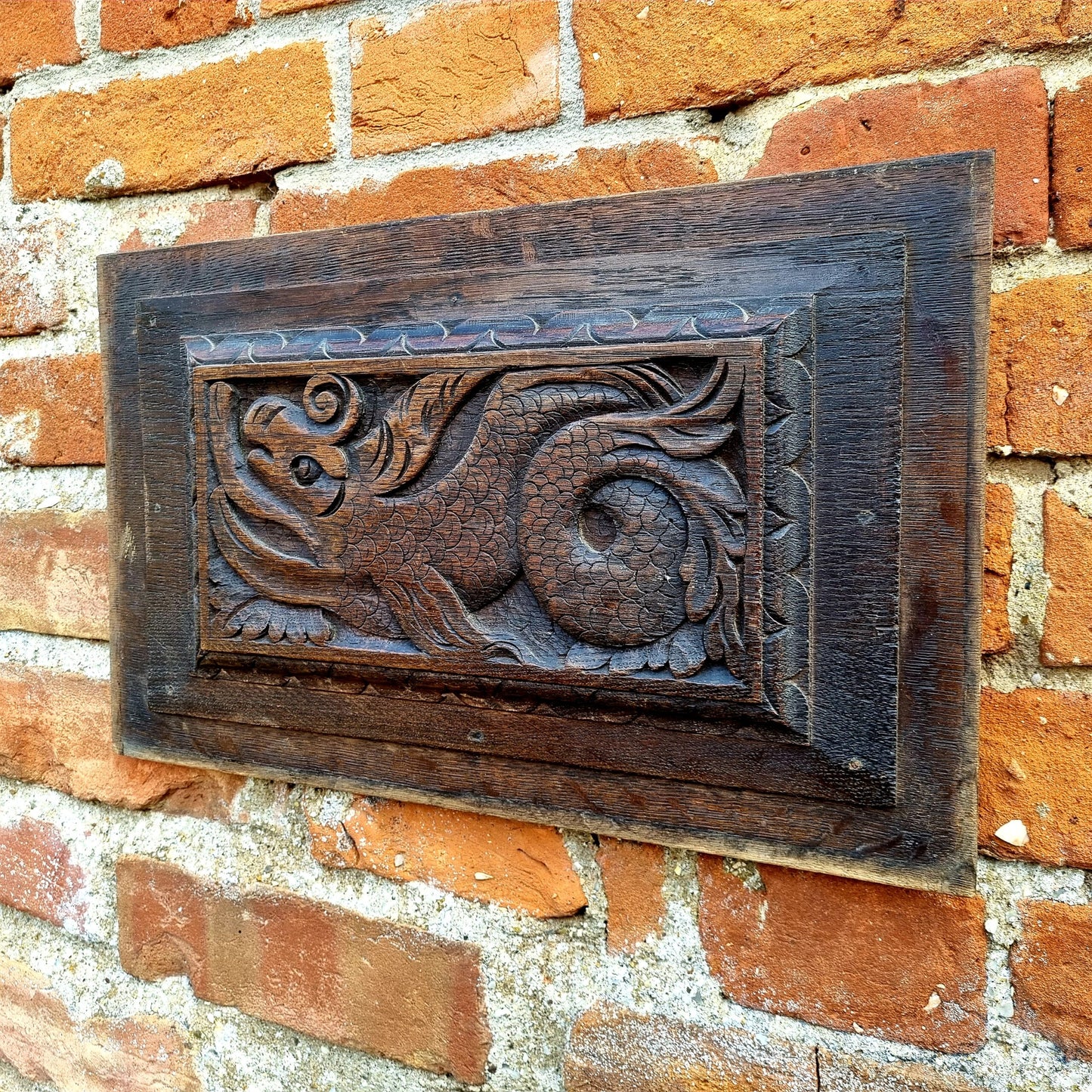 A pair of early 17thC antique carved oak panels depicting stylised mythical sea creatures