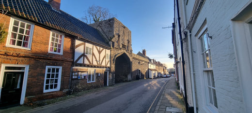 A view of the High Street in Little Walsingham, Norfolk and the medieval entrance to the Priory.