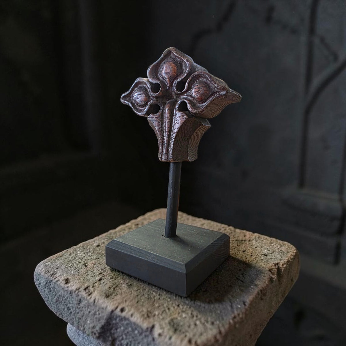 Victorian Gothic Revival carved oak foliate finial on an ebonised stand, displayed on a weathered stone plinth against a dark background