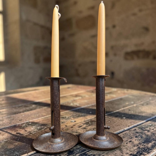 Holt Antiques at Walsingham Mill pair of adjustable dark iron candle holders with taper candles on a rustic table