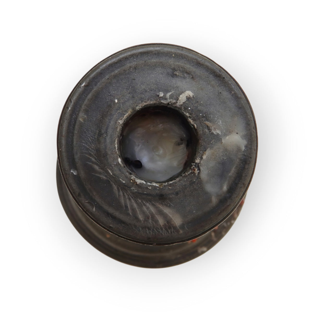 Topside detail of the pewter candlestick's drip-pan and socket, showing old wax residue and seam lines