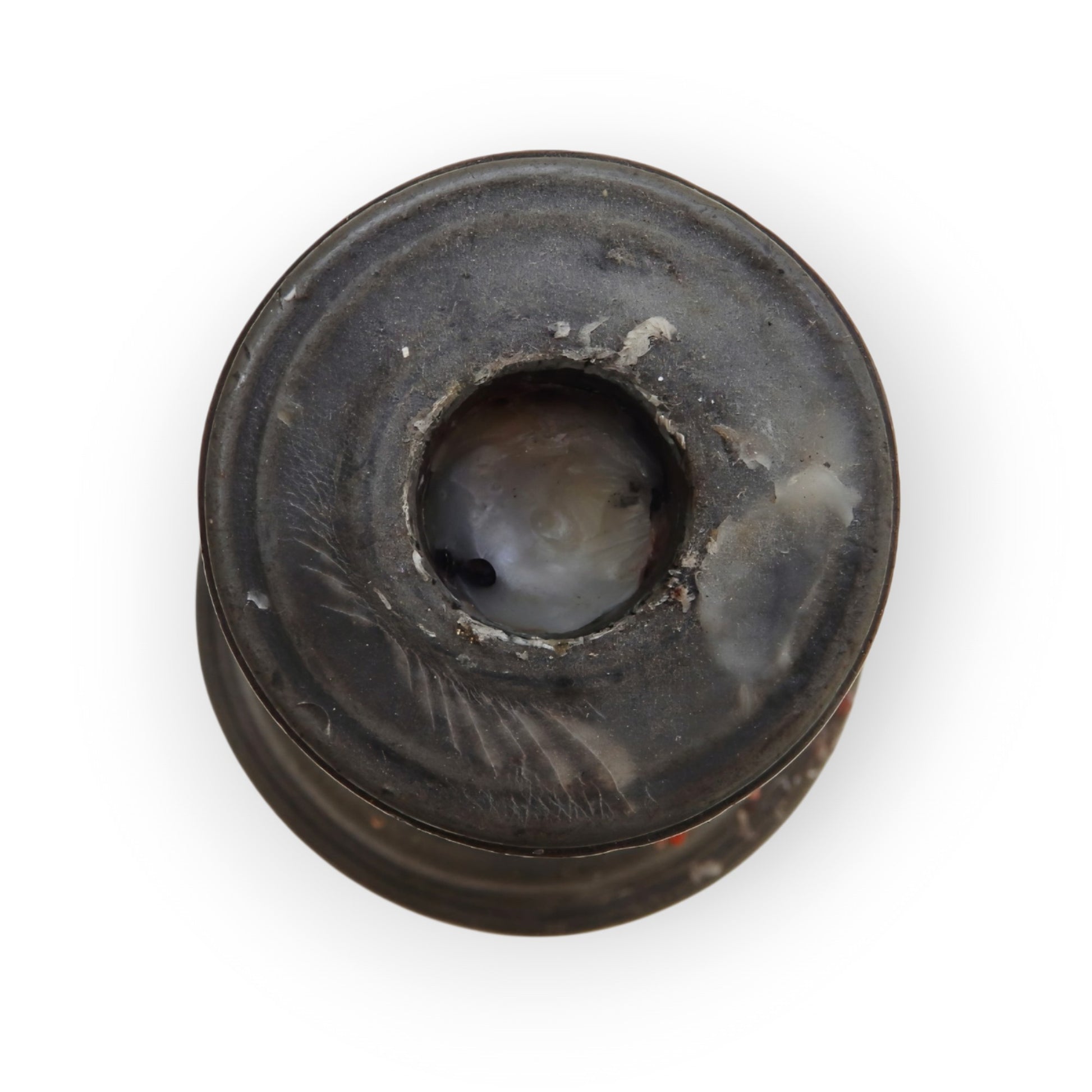 Topside detail of the pewter candlestick's drip-pan and socket, showing old wax residue and seam lines