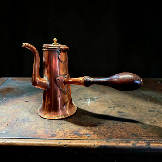 18th century Continental copper coffee pot with swan-neck spout and turned wooden side handle on a worn wooden surface against a dark background.