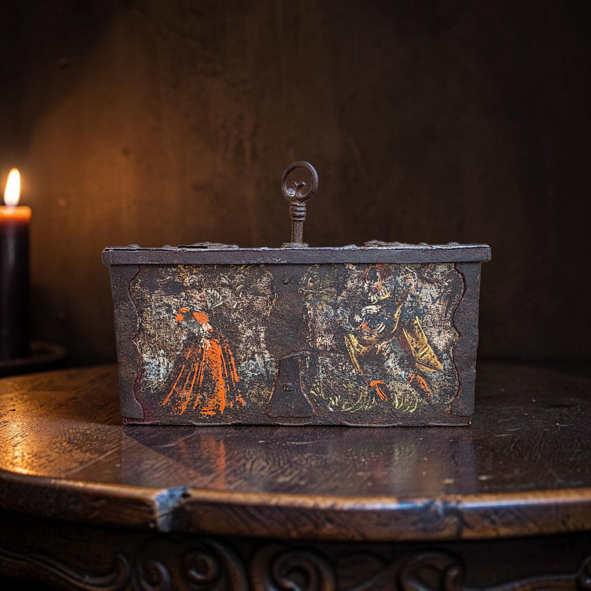 Nuremberg painted iron table casket, circa 1580, front view showing figural decoration and ring carrying handle, photographed on a wood surface