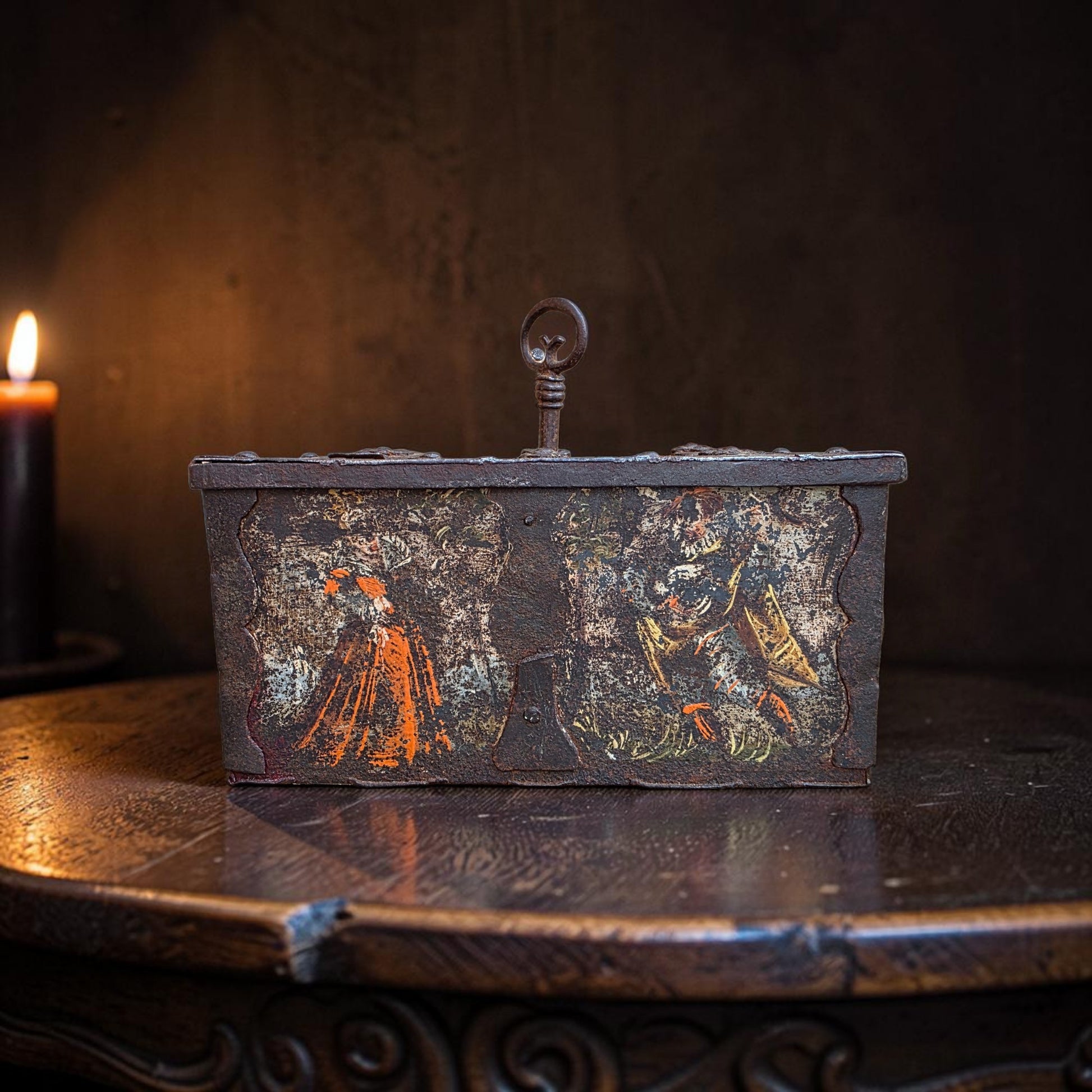 Nuremberg painted iron table casket, circa 1580, front view showing figural decoration and ring carrying handle, photographed on a wood surface