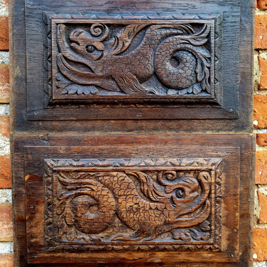 A pair of early 17thC antique carved oak panels depicting stylised mythical sea creatures